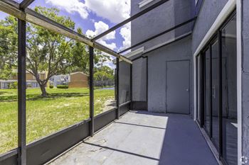 the patio of a building with glass doors and a grass field